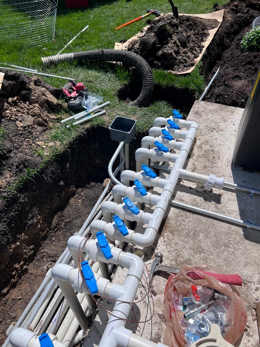 Underground utility lines run in an open trench before backfill